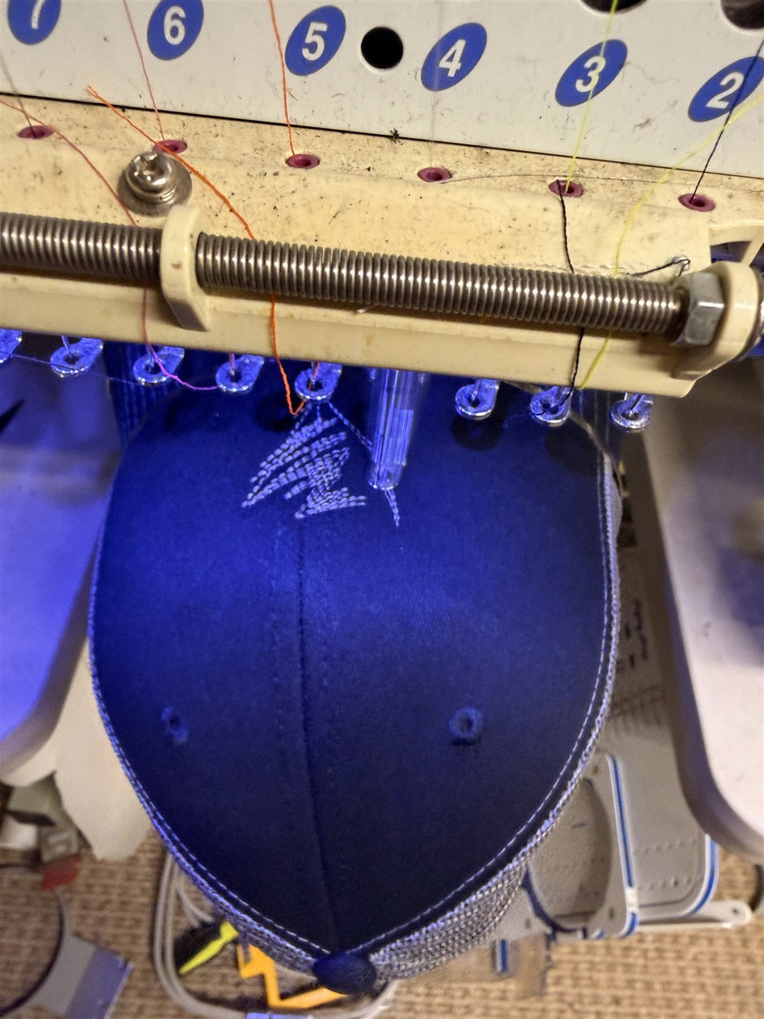 Hat hooped and stitching on a multi-needle embroidery machine at Battle Born Clothing in Yerington, Nevada